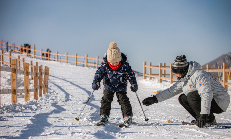 A child learning to ski with a parent in Xinjiang