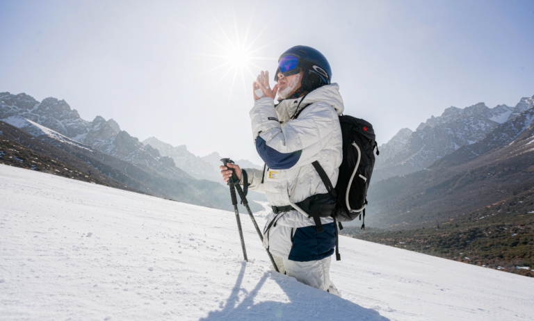 A skier on a high sunny snow slope in Xinjiang wearing goggles and sunscreen