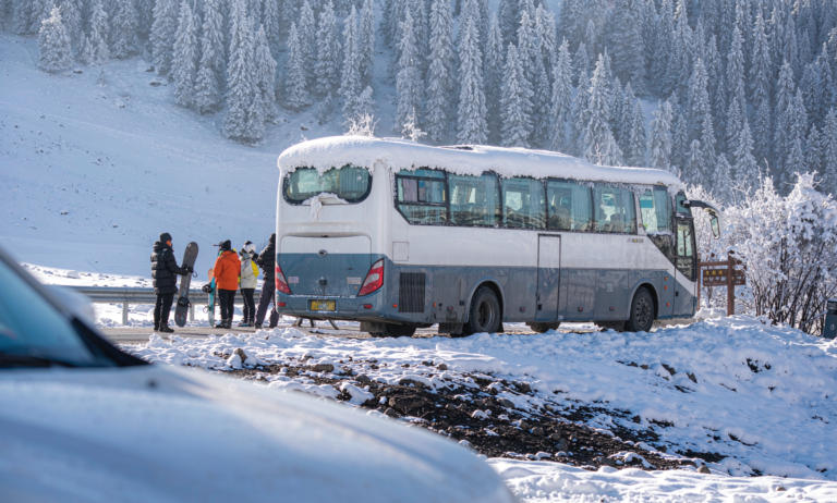 A long-distance coach bus at a snowy stop near ski resorts in Xinjiang